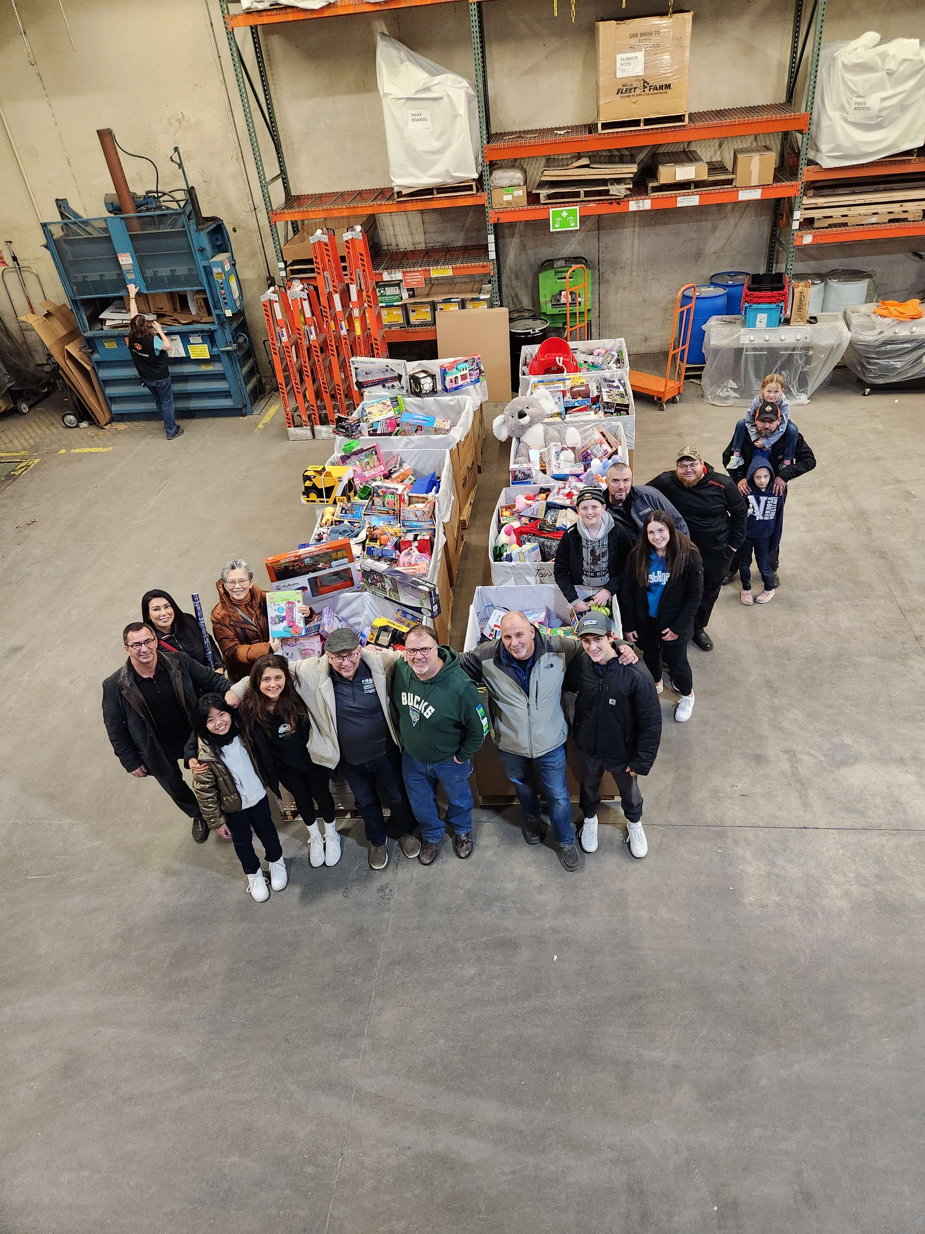 Team members and families with stacked toy donations